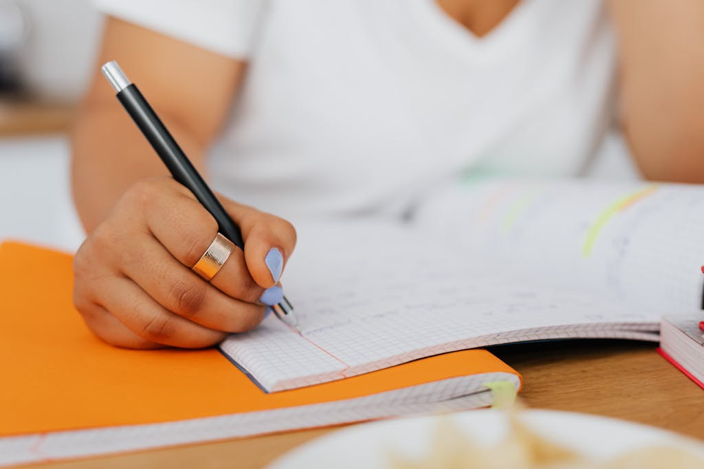 Detailed shot of a woman's hand writing in a notebook, ideal for education-themed content.